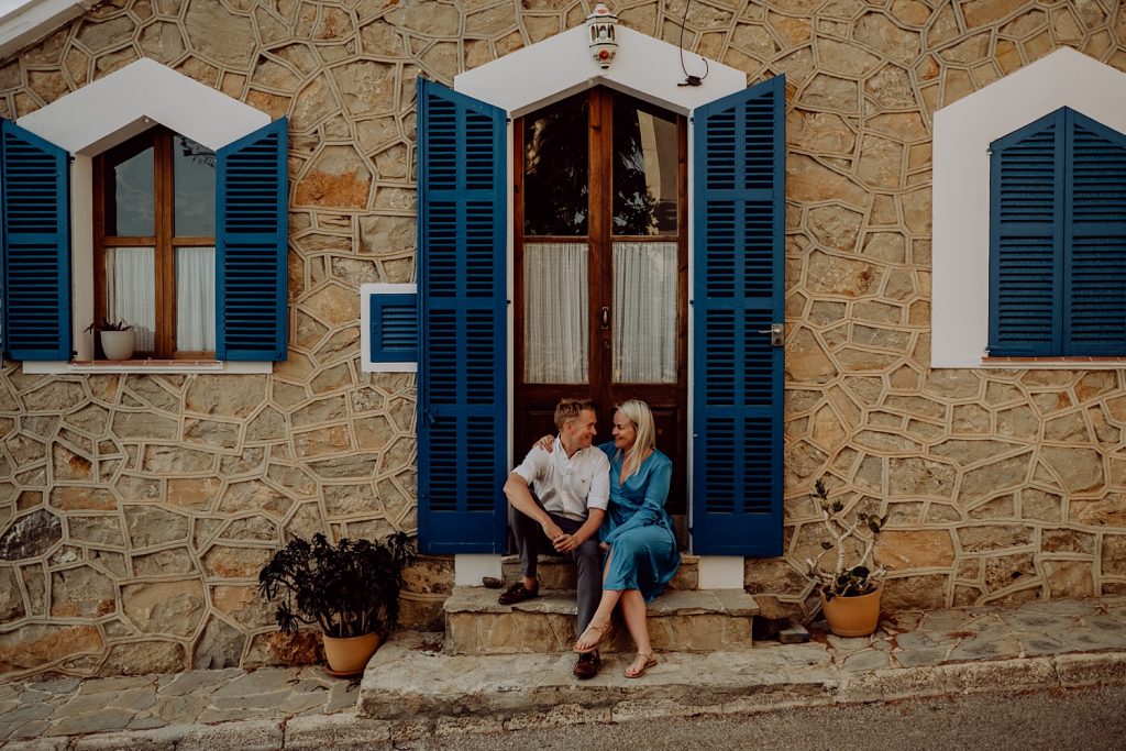 Couple sitting outside a house with blue shutters in sant elm mallorca